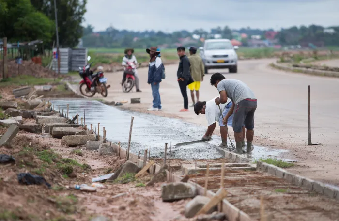 local workers pouring concrete to make a pavement in Lao