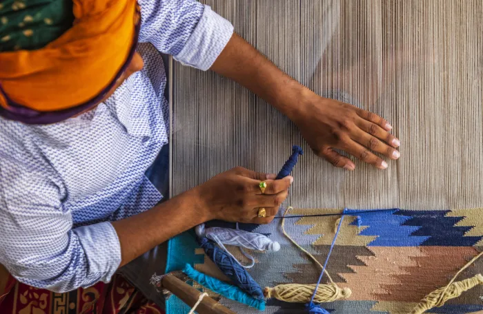 Indian man weaving durries