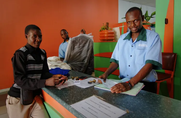 Two male workers and a male customer at a laundry shop.