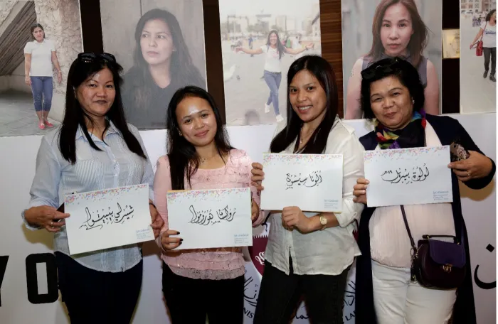 Four women holding signs in Arabic for Domestic Workers' Day celebration in Doha, Qatar