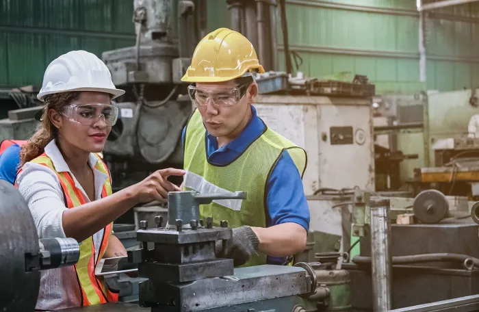 Man and woman engineer industry worker wearing hard hat in factory