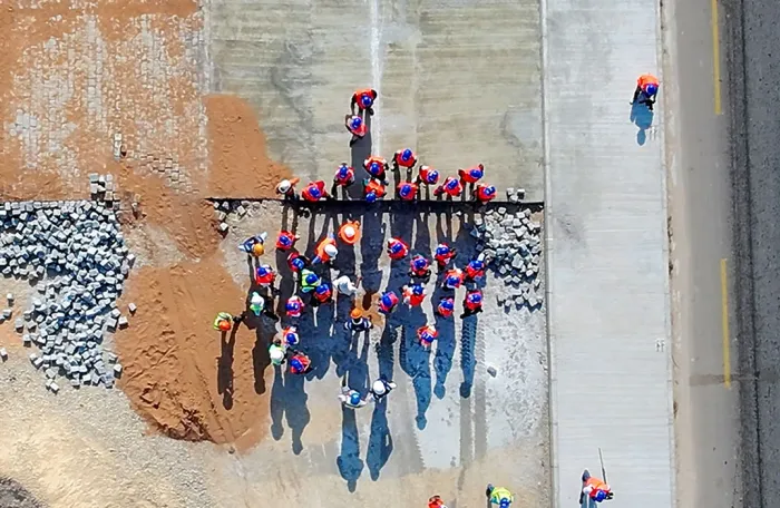A drone shot of journalists visiting a road construction site in northern Madagascar, seen from above with the road beside them.