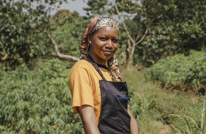 Woman farmer posing infront of a farm and smiling at the camera