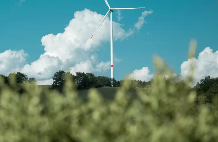 Wind turbine with blue sky in the background and greens on the foreground 