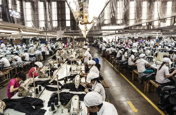 Wide shot of the garment factory featuring row of busy workers 