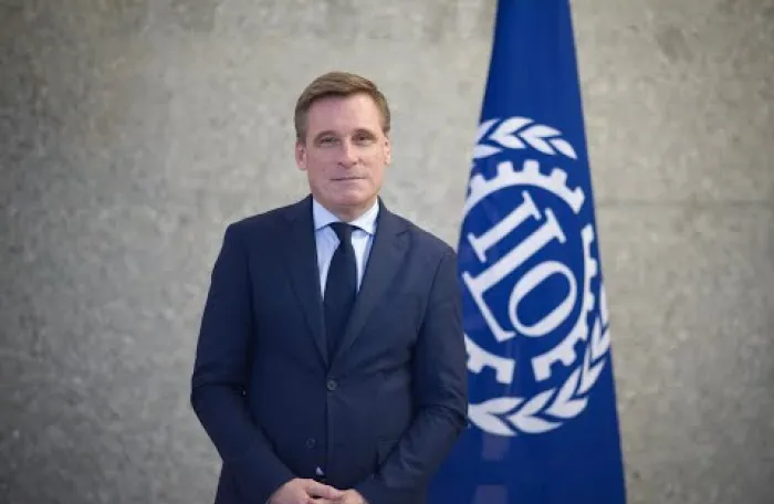 Man in suit in front of ILO flag - Oliver Röpke ACTRAV Director