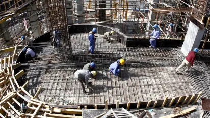 Migrant workers lay down supporting rods for a floor at a construction site in Doha.