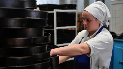 Young woman cleaning cake moulds.