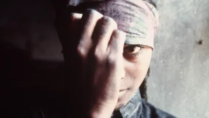 Woman in forced labour partially covering her face with her hand.