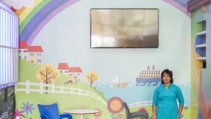 A Sri Lankan woman in front of a children's playroom mural, in Qatar