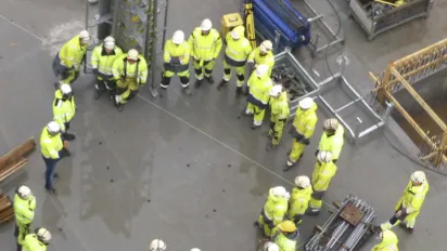 Men in building outfits are standing in a circle on a construction site