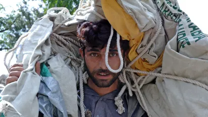 young man carrying bags and ropes on his shoulders.Pakistan