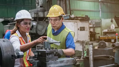 Man and woman engineer industry worker wearing hard hat in factory