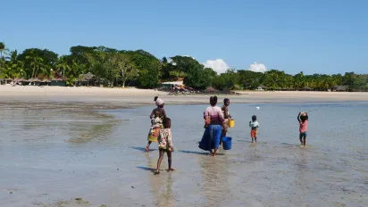 Des enfants et leur mère avancent dans l'eau transparente.