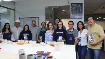 Grupo de once personas (seis hombres y cinco mujeres) posan para una foto en un laboratorio de café. 