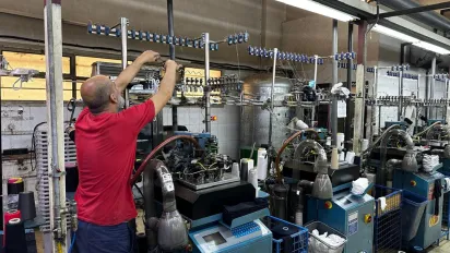 A man reaches over top of a machine at a textile factory in Syria