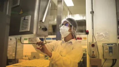 Worker with full PPE gear looking at a control screen in the Philippines