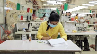 Woman worker taking notes on a logbook in a garment factory
