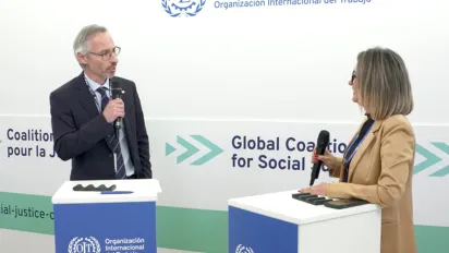 ILO Director of communication stands next to Government Delegate from Paraguay in front of an ILO branded backdrop