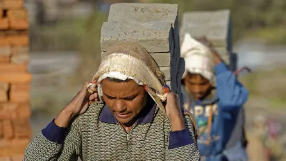 Two men carrying pieces of bricks in the suburbs of Kathmandu, Nepal.