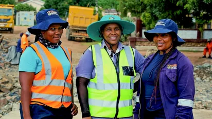 Three South African female workers on an ILO Employment Intensive Investment Programme project smile at the camera.