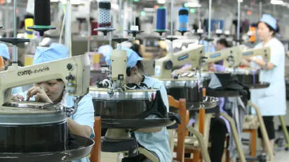 Garment workers assembling clothing using industrial sewing machines at a garment factory in Mongolia.