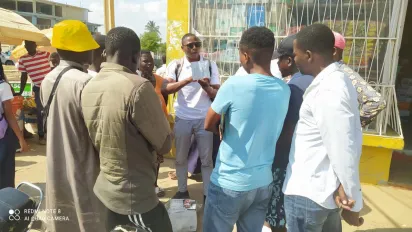Group of young men gathered around ECOSIDA peer educator