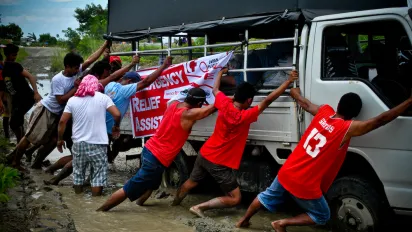 A group of volunteers helping a truck get out of the mud