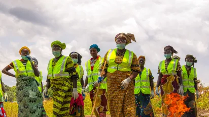 Des travailleuses agricoles en Côte d’Ivoire se tiennent dans un champ, portant des gilets de sécurité, des lunettes de protection, des masques et des gants, soulignant l’importance de conditions de travail sûres et respectueuses.