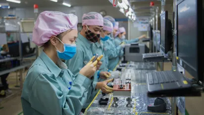 Workers assembling electronic components on a factory production line.