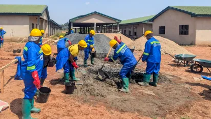Female trainees at the Bamenda 3 training worksite mix mortar for the starter pillars of a market shed as part of an International Labour Organization youth employability project in Cameroon.