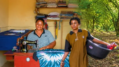 A young woman, Obassey Divine, stands in a cocoa plantation while another woman,Blessing Thomas, sits at a sewing machine in her tailoring shop in Nigeria.
