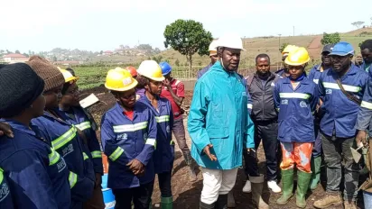 Nkambe mayor speaks with road rehabilitation workers wearing safety gear.