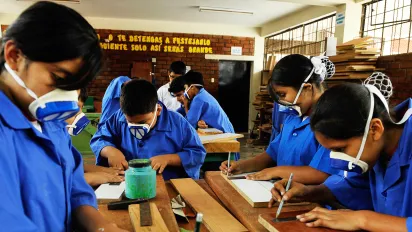 Students wearing protective masks measure and work on wooden boards during a woodwork class at the Fe y Alegría school in Lima, Peru.