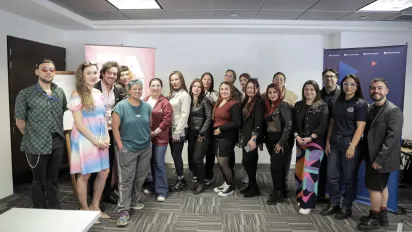 Grupo de personas posan de pie para la foto. De fondo se ven los pendones de OIT y Fundación GAAT. 