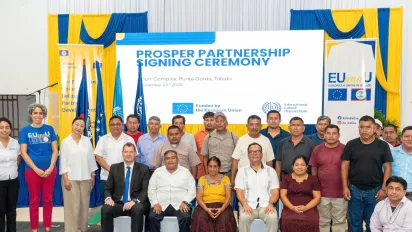 A group of persons standing in rows in front of a large sign