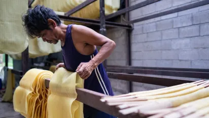 Phong, a worker in eastern Thailand, dried rubber sheets and prepared them for sale. The sheets are stacked in neat piles in a shed, awaiting collection by a trader.