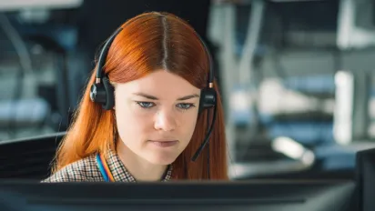 Young woman with a headset in front of a computer 