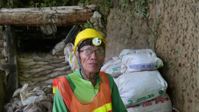 A worker in mining wearing a yellow hard hat.
