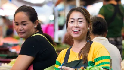 Two women sell fresh vegetables at a market. 