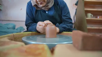 A woman shapes a ceramic piece at a pottery wheel during a visit to a women-led ceramics initiative in Petra, Jordan.