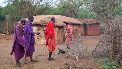 Maasai men leave the homestead as they speak with a woman who remains behind with a child, reflecting gendered patterns of mobility and care responsibilities in pastoral communities in Kenya