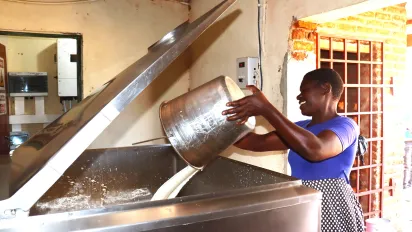 Woman throwing milk into machine, Malawi