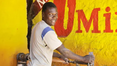 Kenyan man in workshop smiling at camera.