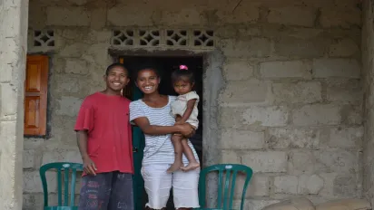 A family in Timor-Leste smiling in front of their house