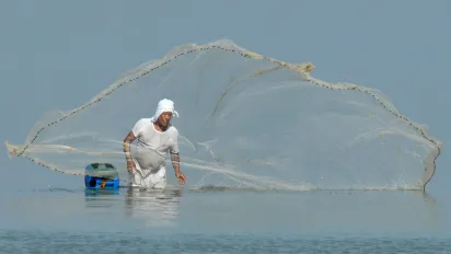 man casting his net in the sea