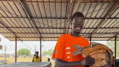 Alphonso Lado Modi, a beneficiary of a FAO project in South Sudan holds up a dried fish