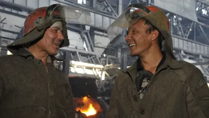 Two men with protection gear have a chat at a working site.