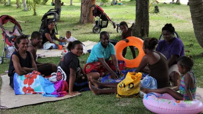Mothers and their toddlers spending a Sunday afternoon under the palm trees next to the beach, Vanuatu.
