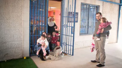 A father holds his child as other children leave a daycare in Amman, Jordan